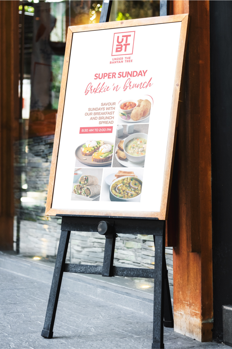 UTBT restaurant sidewalk menu board advertising Sunday brunch special with food photos on wooden easel stand