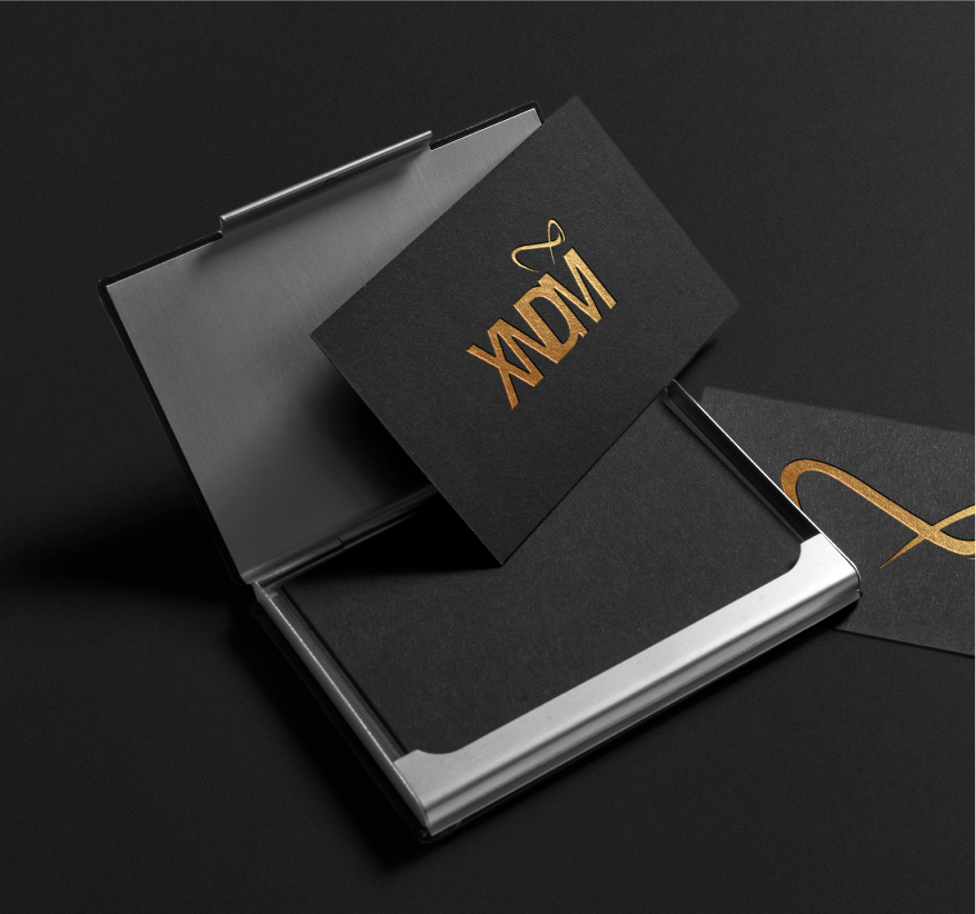 Elegant black business cards and stationery with gold XNDM logo displayed in an open presentation box.