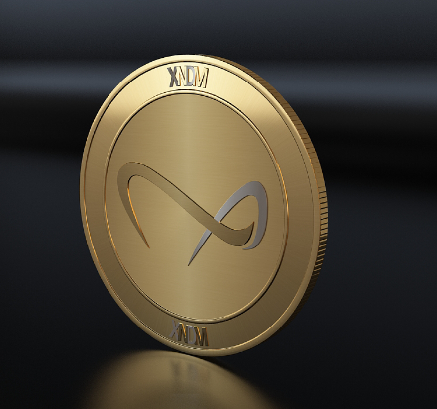 Gold XNDM cryptocurrency coin with infinity symbol logo displayed at an angle on reflective surface.
