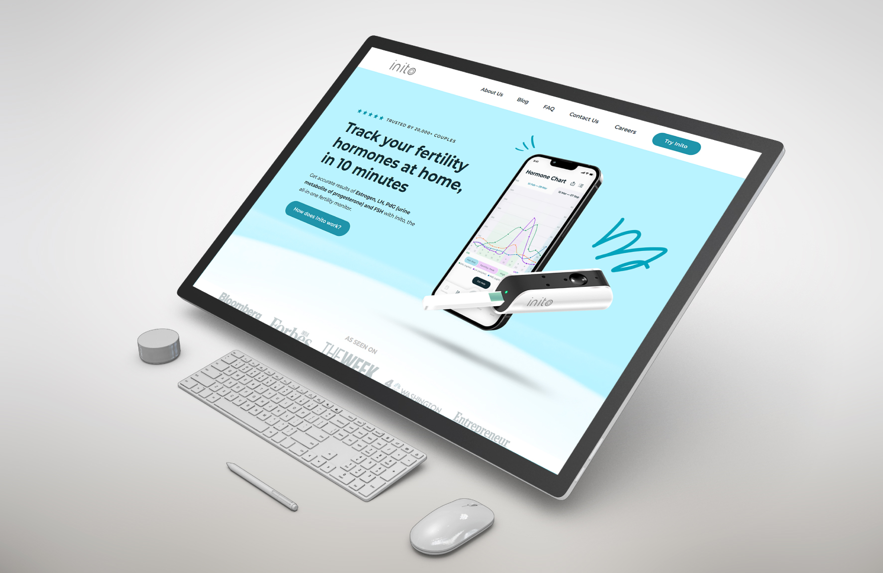 Monitor displaying Inito website about tracking fertility hormones at home, with a keyboard, mouse, and fertility device visible.