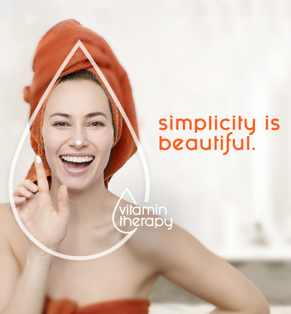 Smiling woman with orange towel applying skincare product, "simplicity is beautiful" and "vitamin therapy" text