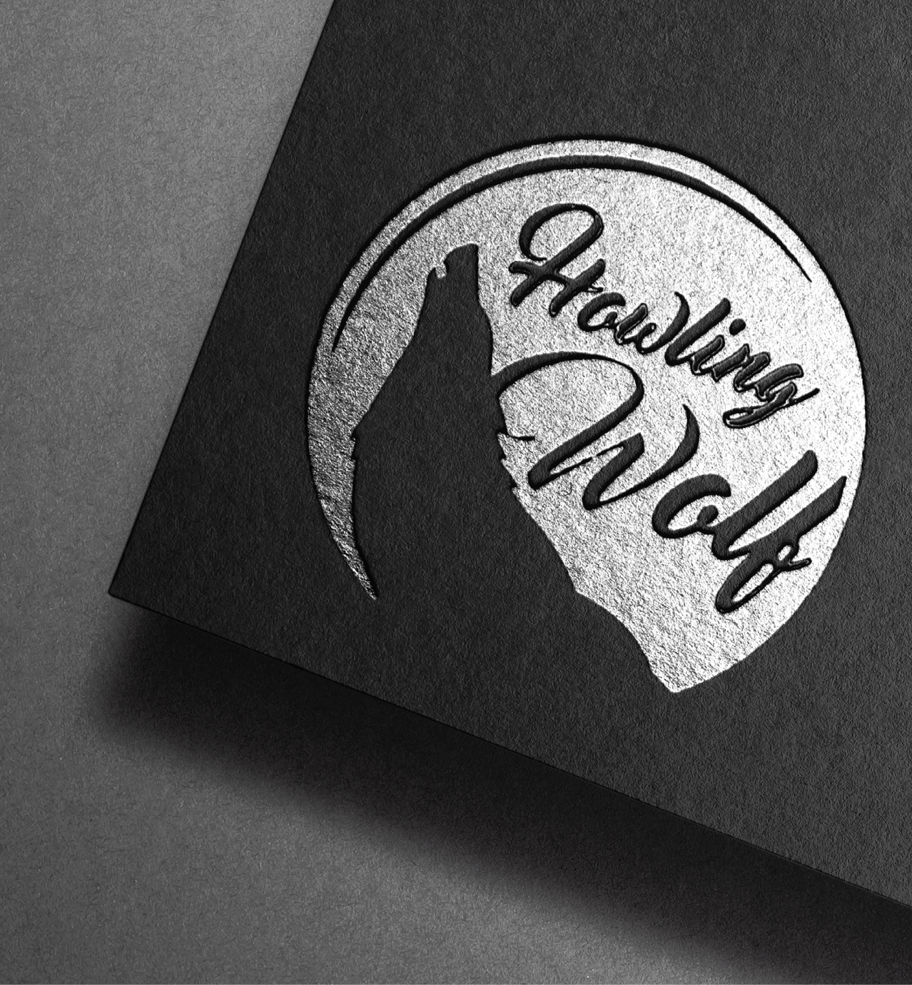 Metallic embossed "Howling Wolf" logo with a silhouette of a howling wolf inside a circular design on black paper.