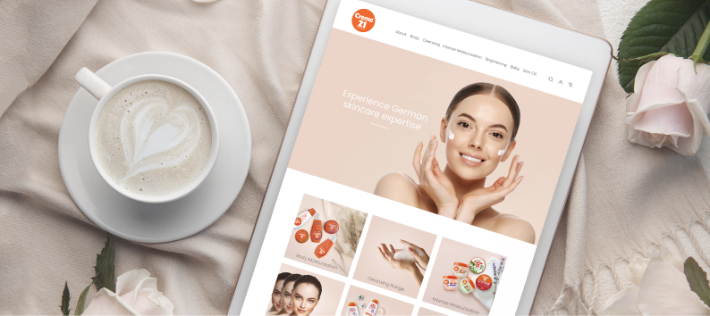 Tablet displaying a skincare website beside a cup of latte and pale pink roses on a soft fabric surface.