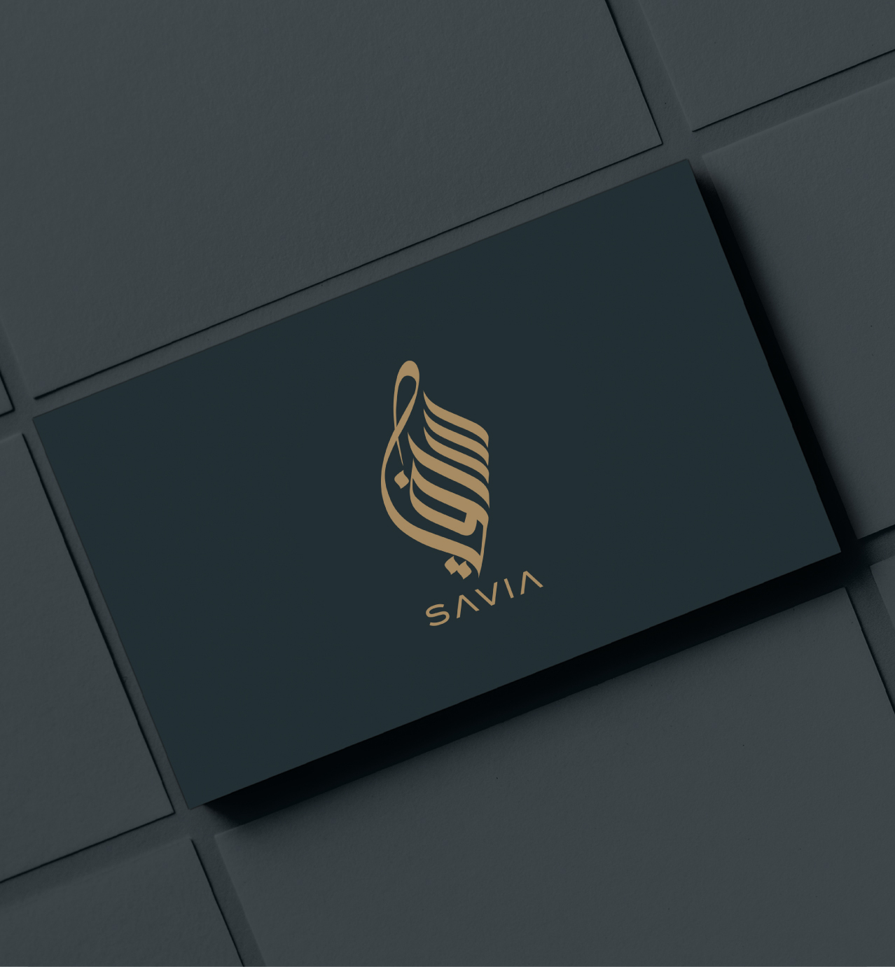 Elegant SAVIA business card with gold stylized Arabic calligraphy and modern text on a dark background.