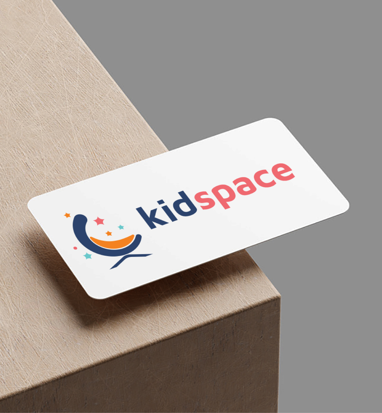 Kidspace logo on a white card with playful text and a colorful crescent moon and stars graphic, placed on a wooden surface.
