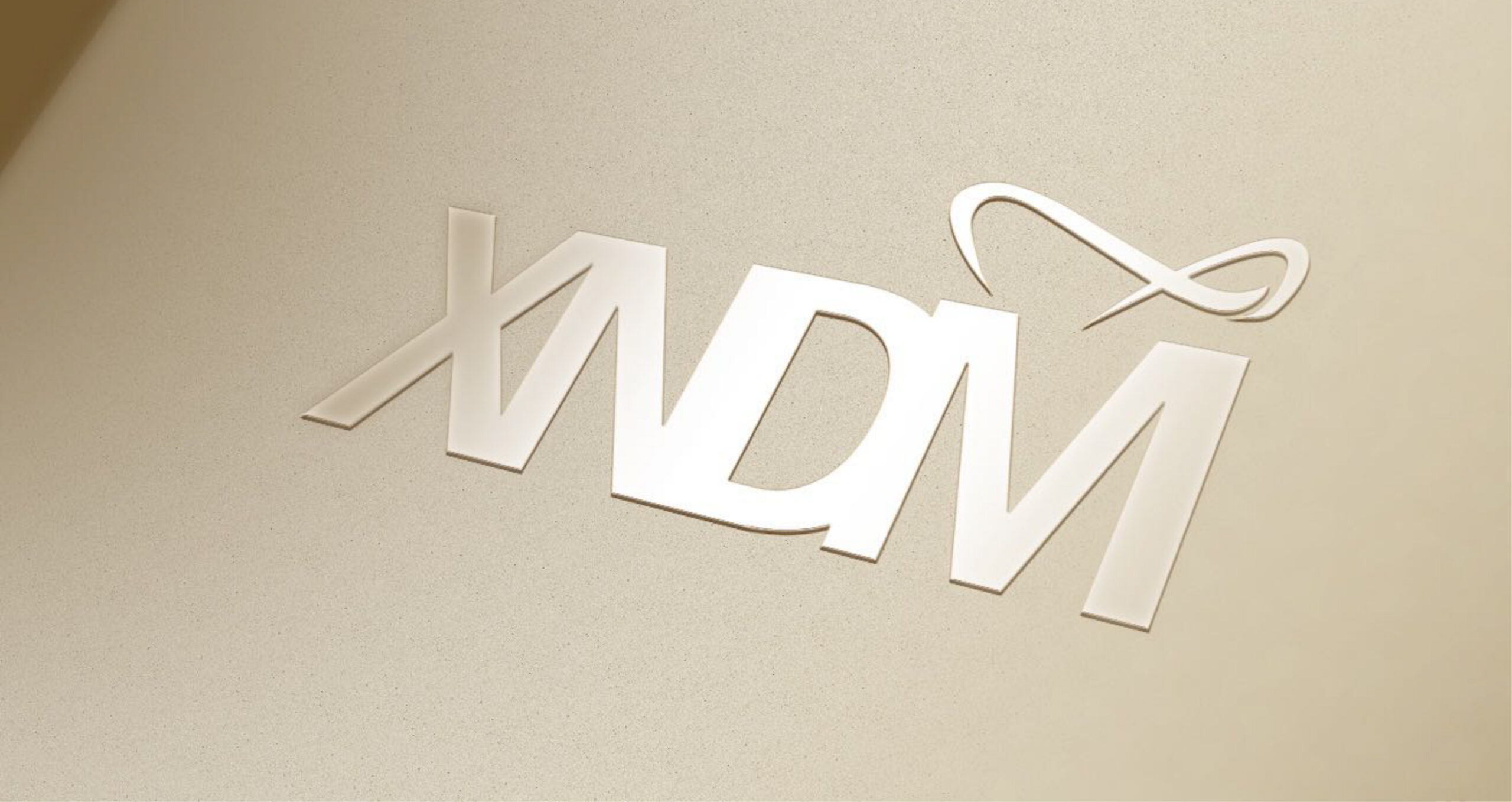 Sleek, metallic XDM logo with modern lettering and a swoosh accent above the M on a beige textured background.
