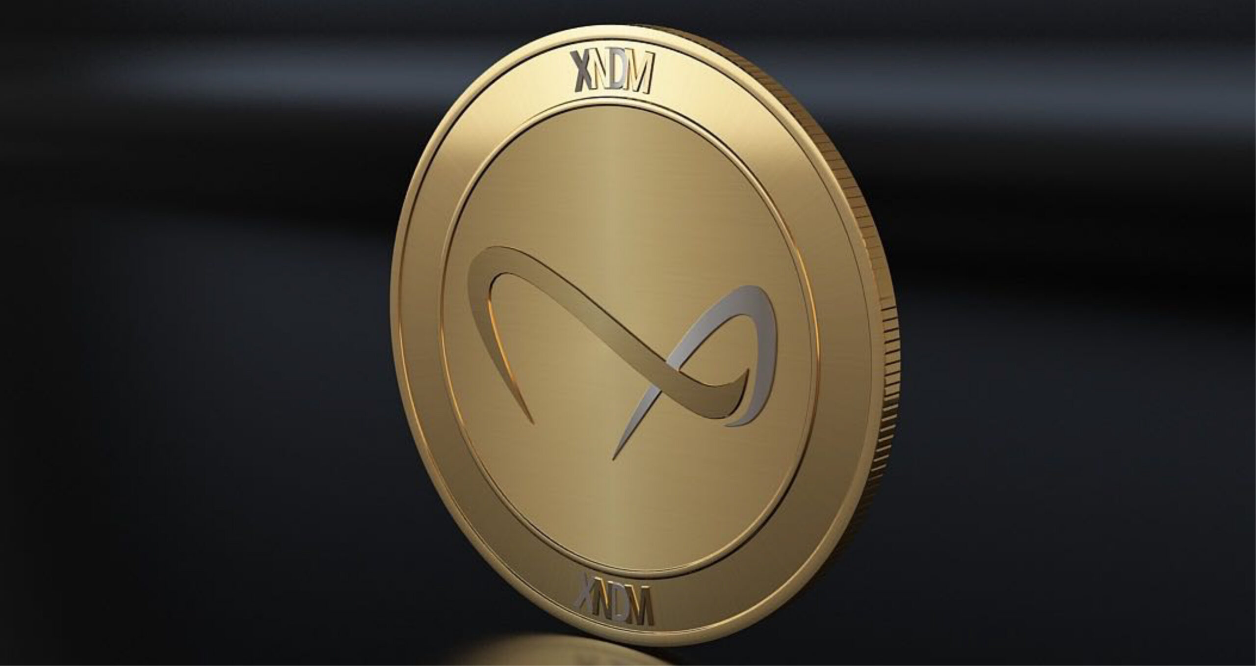Gold coin with an infinity symbol in the center and "XNDM" engraved at the top and bottom, shown on a dark background.