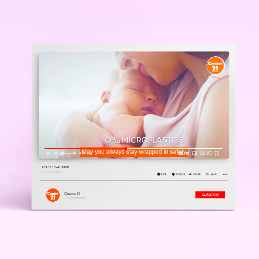 A mother cuddles her baby in a Creme 21 video ad, highlighting "0% microplastics" and safety for delicate skin.