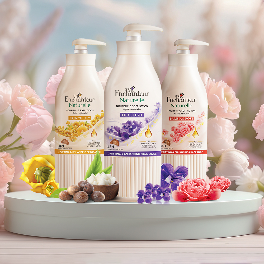 Three Enchanteur Naturelle lotions French Lily, Lilac Lush, and Parisian Rose displayed with flowers and shea nuts.