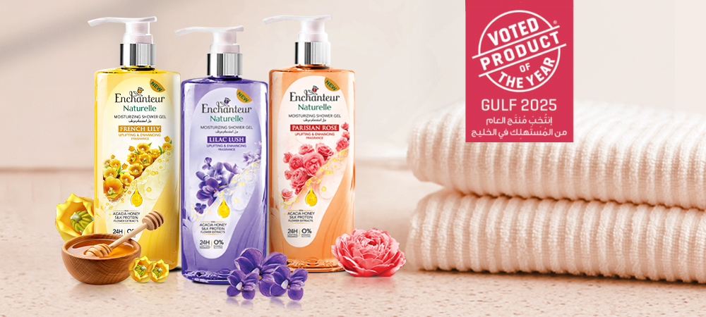 Three Enchanteur Naturelle shower gels French Lily, Lilac Lush, Parisian Rose—displayed with flowers, honey, and towels.