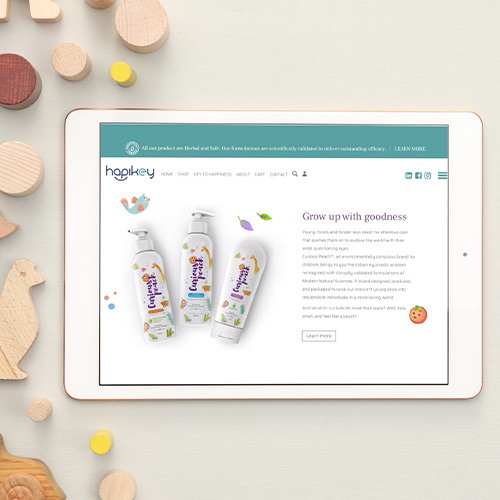 A tablet displays the hapikey website with baby care product bottles and a "Grow up with goodness" message.
