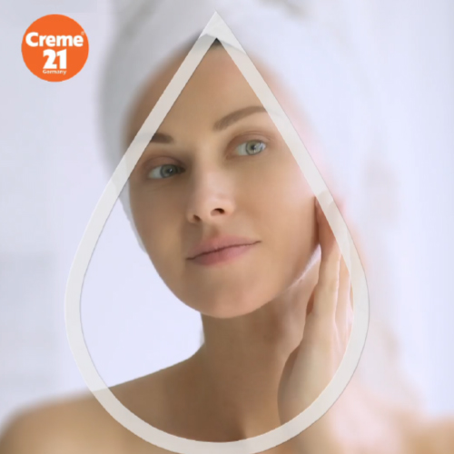 Person applying skincare inside a droplet frame, with Creme 21 logo in the top left corner.