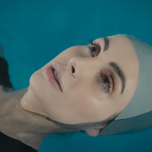 A swimmer gliding underwater in a pool, with clear turquoise water surrounding their body.