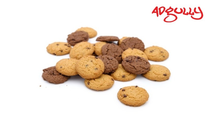 Pile of chocolate and vanilla cookies on a white background with the red Adgully logo in the top right corner.