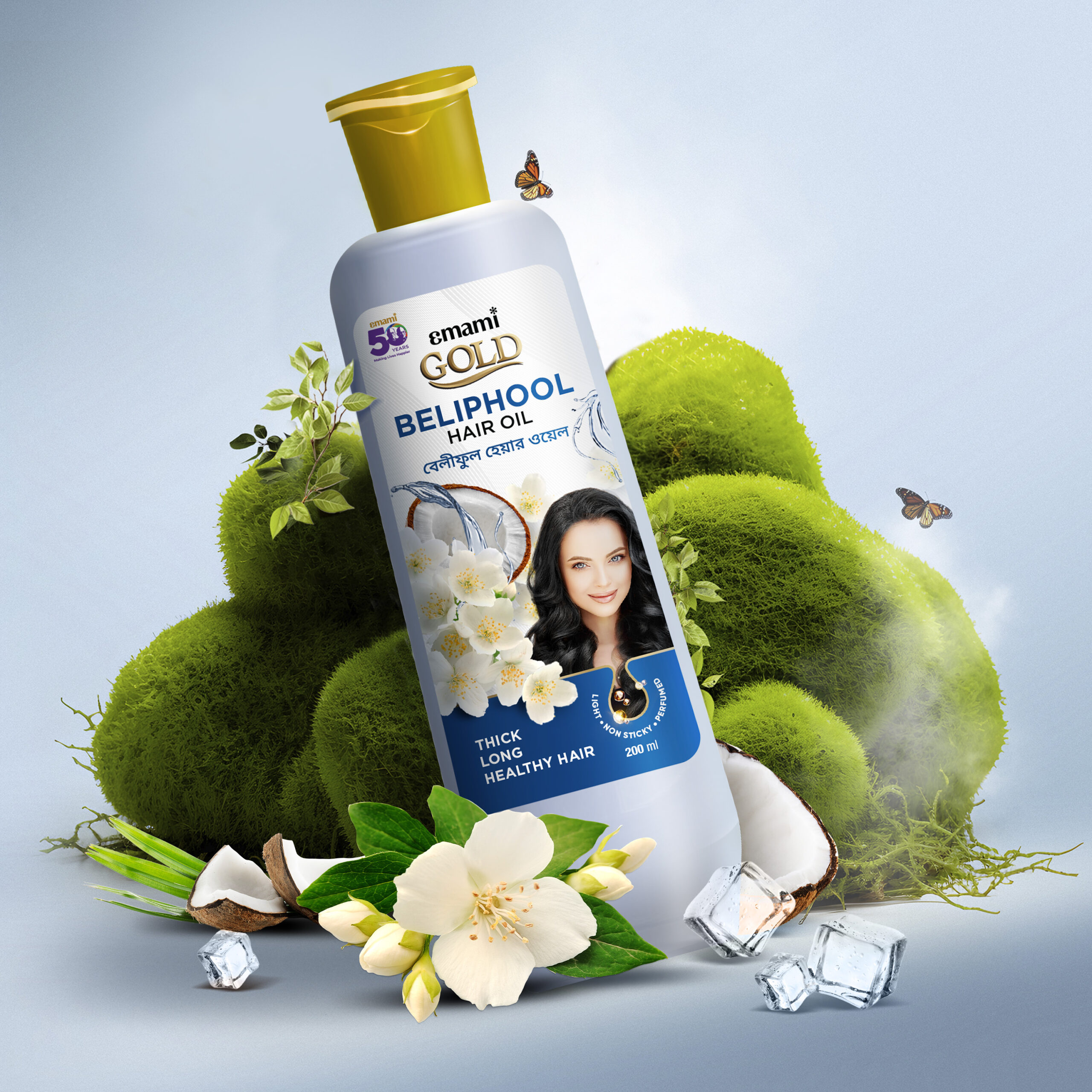 Emami Gold Beliphool Hair Oil bottle with flowers, coconut halves, ice cubes, butterflies, and green moss in the background.