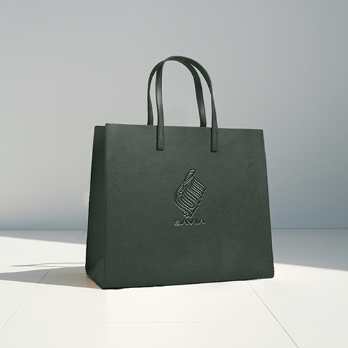 A dark green shopping bag with matching handles features an embossed SAVIA logo and text.
