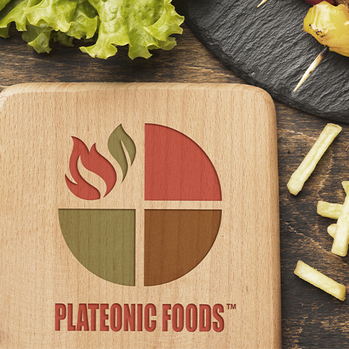 A wooden board features Plateonic Foods logo with four colored segments and a flame design.